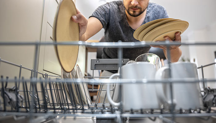 مردی در حال گذاشتن ظروف درون ماشین ظرفشویی